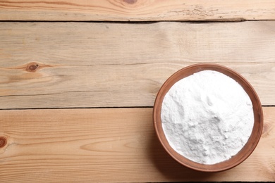 Photo of Bowl with baking soda on wooden table, top view