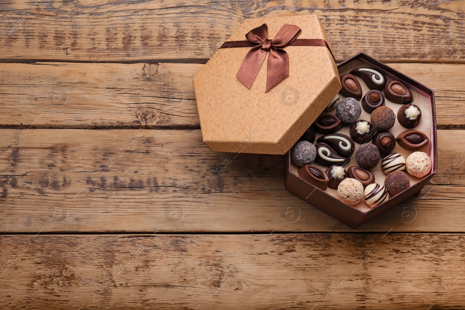 Photo of Open box of delicious chocolate candies on wooden table, top view, Space for text