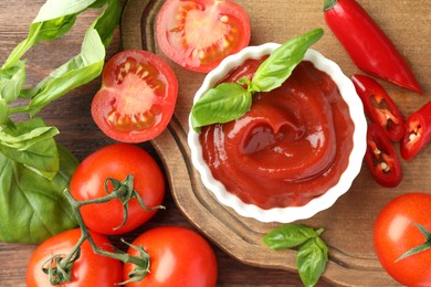 Photo of Bowl of tasty ketchup and ingredients on wooden table, flat lay