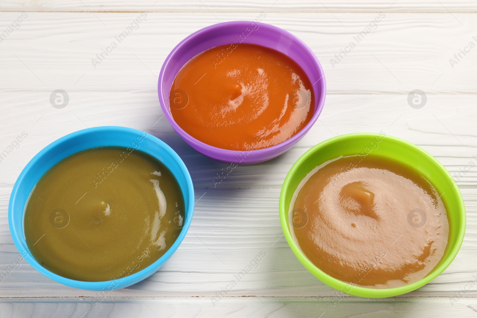 Photo of Baby food. Different purees in bowls on white wooden table