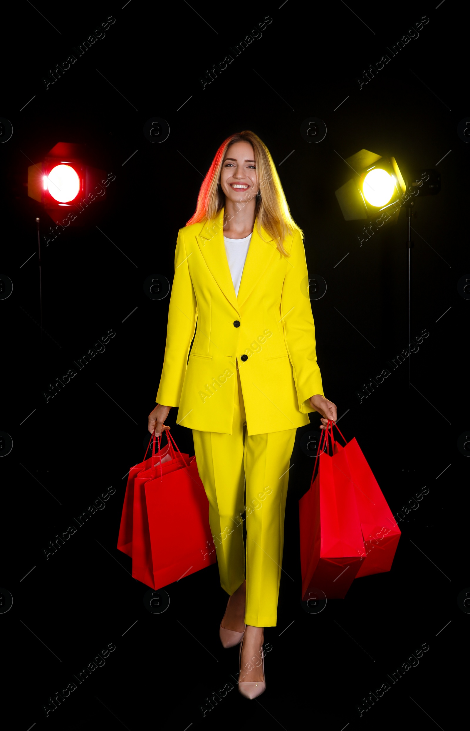 Photo of Happy young woman with shopping bags on dark background. Black Friday Sale