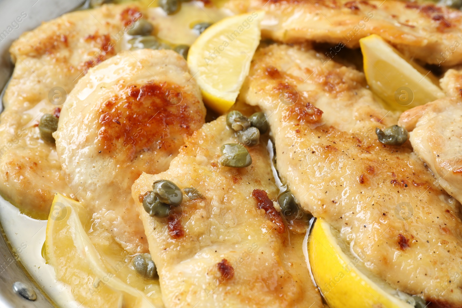 Photo of Delicious chicken piccata with lemons in pot, closeup