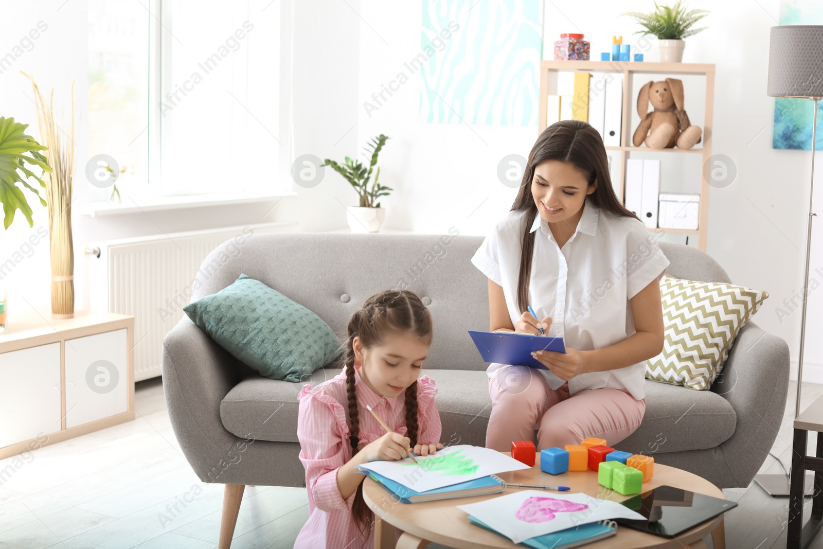 Photo of Child psychologist working with little girl in office