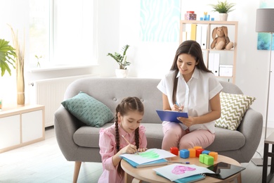 Child psychologist working with little girl in office