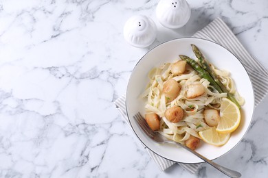 Photo of Delicious scallop pasta served on white marble table, top view. Space for text