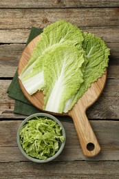 Photo of Cut fresh Chinese cabbage and leaves on wooden table, top view