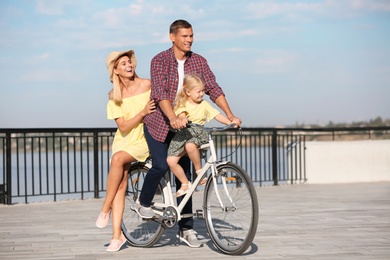 Happy family riding bicycle outdoors on sunny day