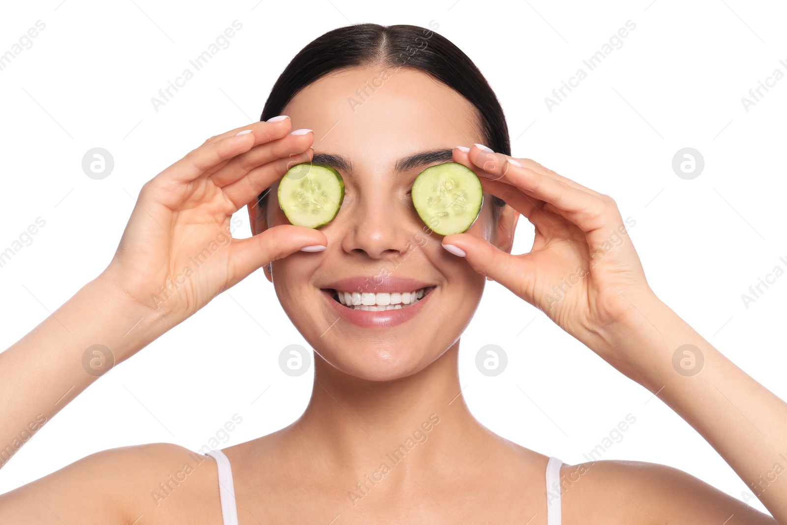 Photo of Beautiful young woman putting slices of cucumber on eyes against white background