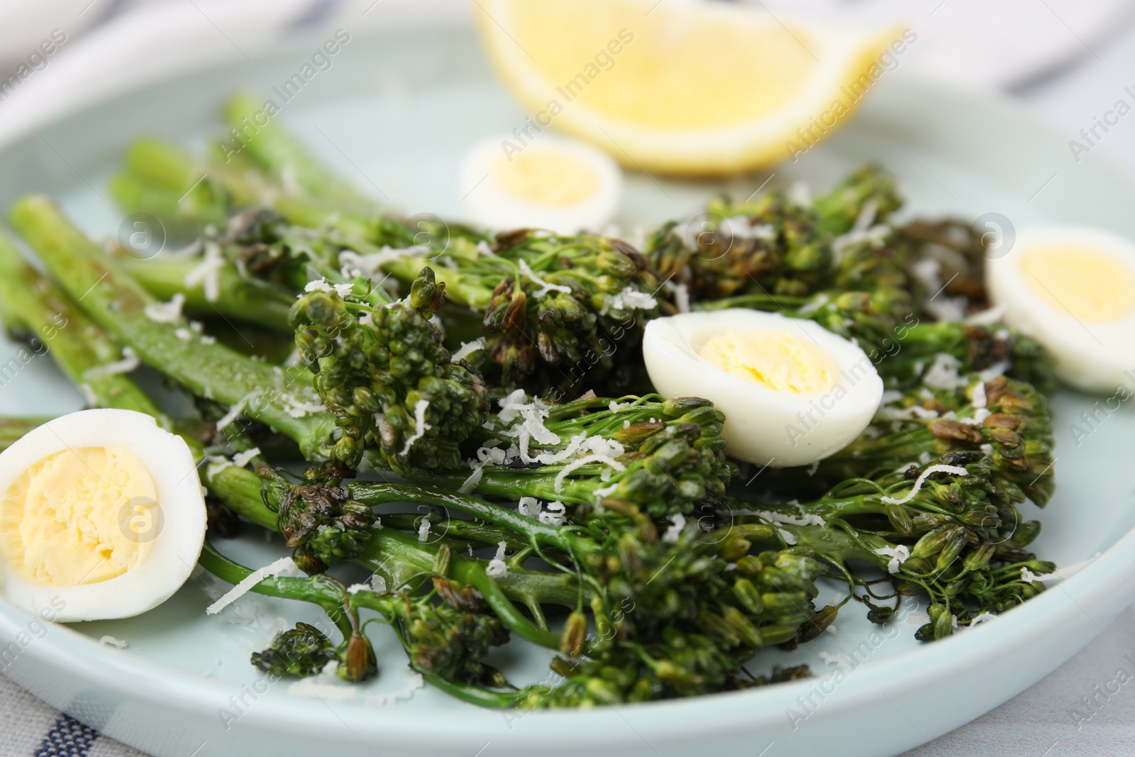 Photo of Tasty cooked broccolini with cheese and quail eggs on plate, closeup