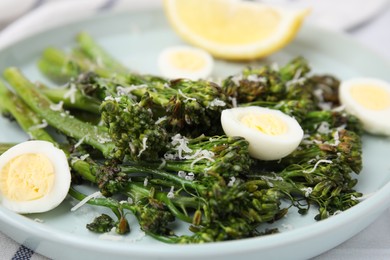 Photo of Tasty cooked broccolini with cheese and quail eggs on plate, closeup