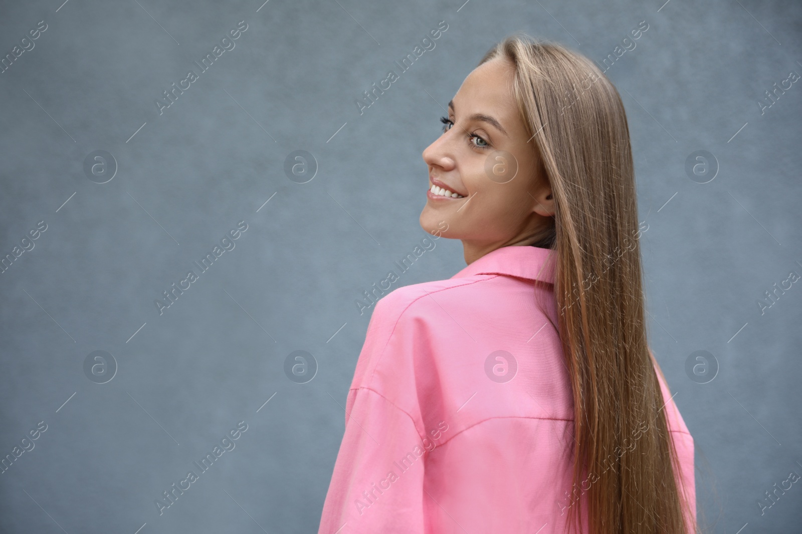 Photo of Beautiful young woman near grey wall, space for text