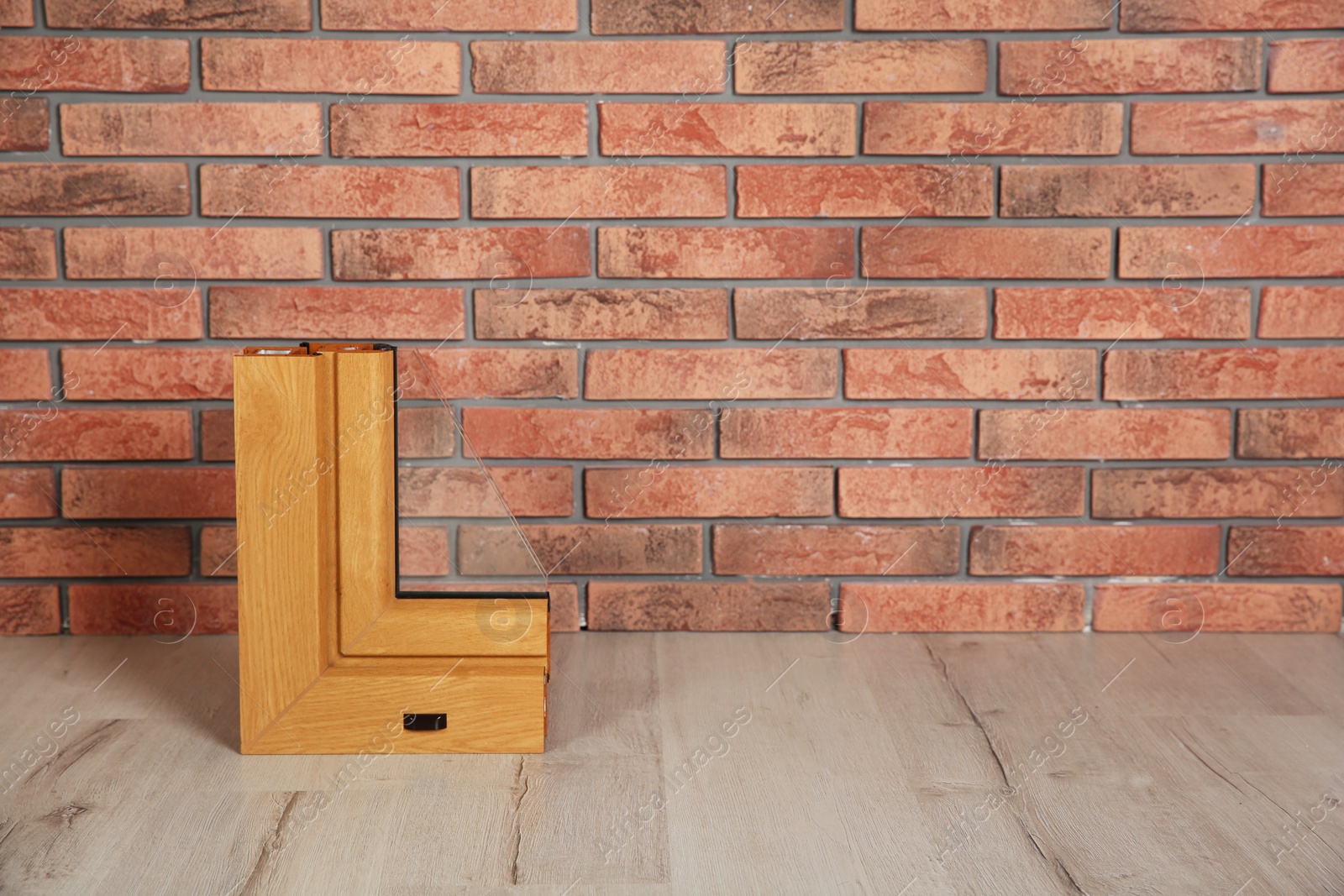 Photo of Sample of modern window profile on floor against brick wall, space for text. Installation service