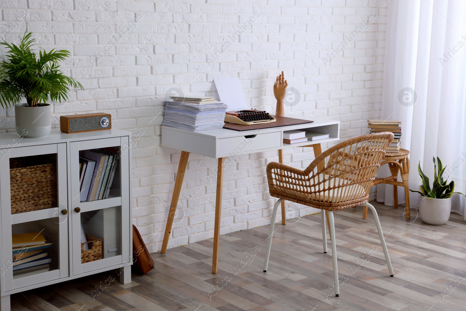 Photo of Comfortable writer's workplace interior with typewriter on desk near white brick wall