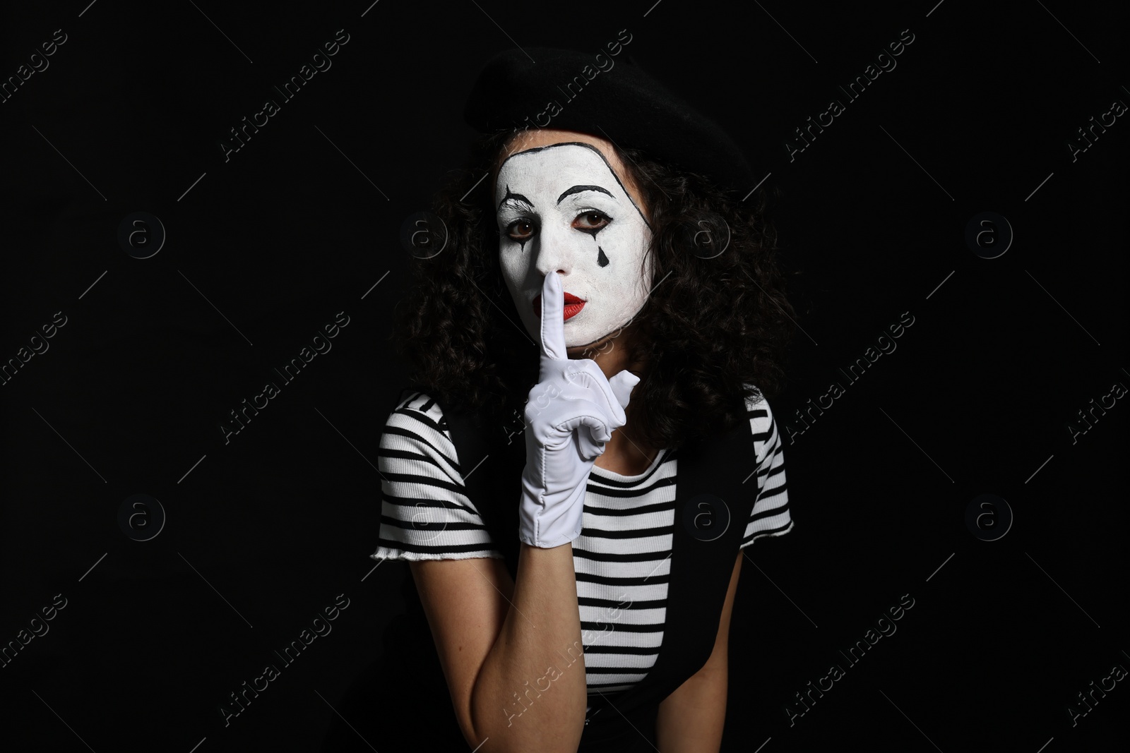 Photo of Young woman in mime costume posing on black background