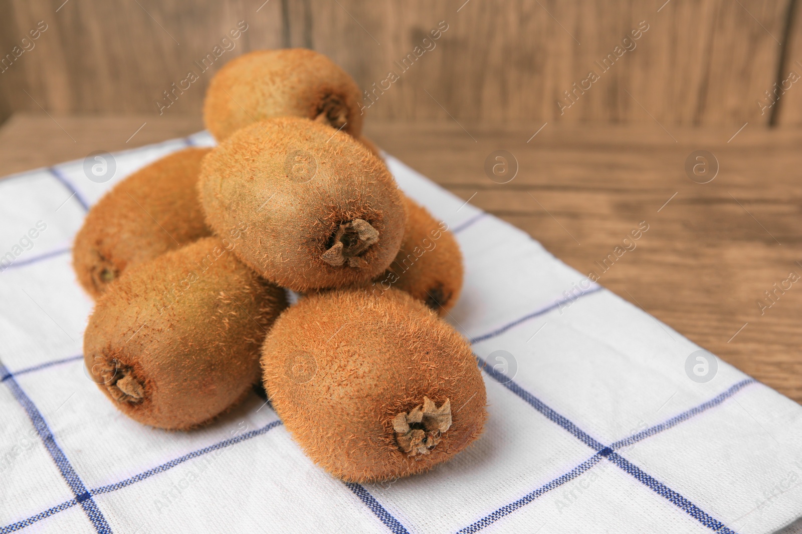 Photo of Heap of whole fresh kiwis on wooden table, closeup. Space for text