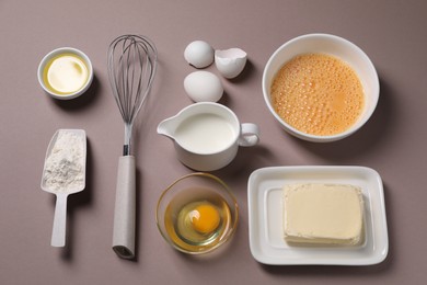 Photo of Composition with whisk and dough ingredients on grey background, above view