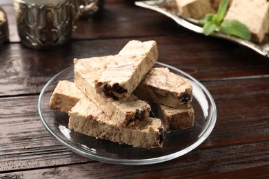 Photo of Glass plate of tasty chocolate halva on wooden table