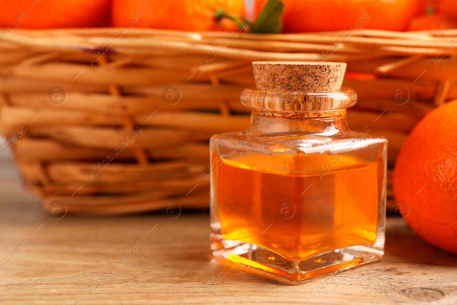 Photo of Bottle of tangerine essential oil and fresh fruits on wooden table, closeup. Space for text
