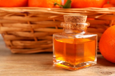 Bottle of tangerine essential oil and fresh fruits on wooden table, closeup. Space for text