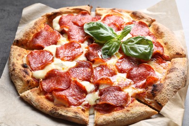 Tasty pepperoni pizza with basil on table