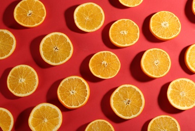 Photo of Slices of delicious oranges on red background, flat lay