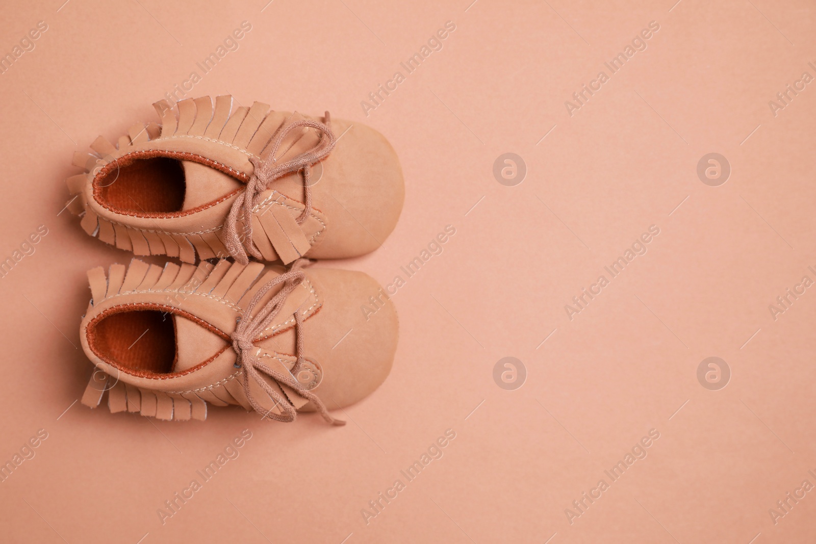 Photo of Cute baby shoes on brown background, flat lay. Space for text