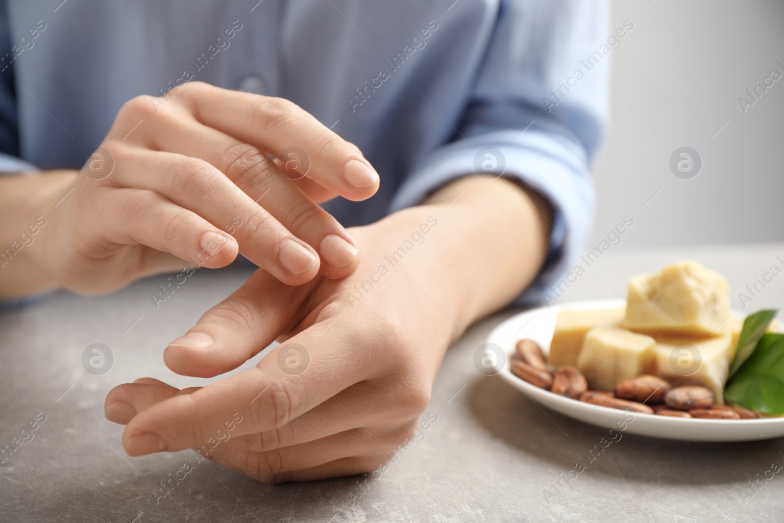 Photo of Woman applying organic cocoa butter at table, closeup