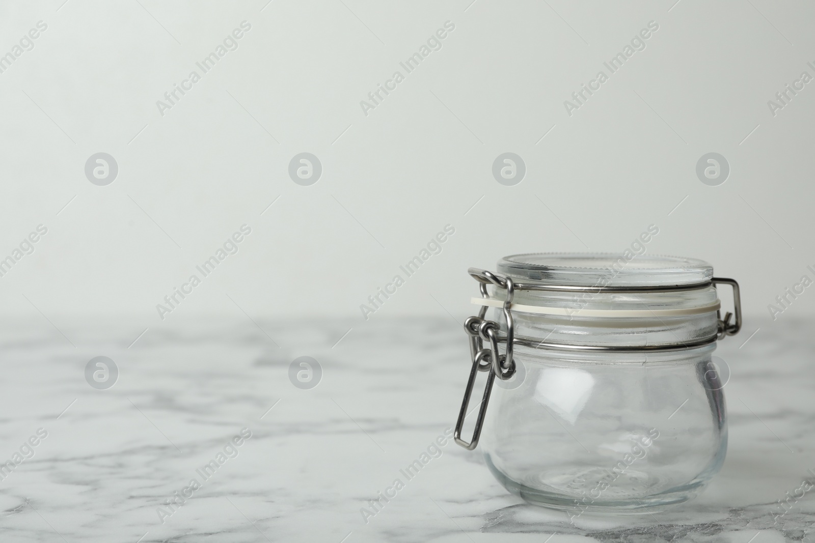 Photo of Empty glass jar on white marble table, space for text