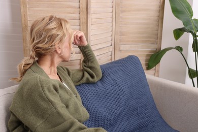 Photo of Woman sulking on sofa in living room. Loneliness concept