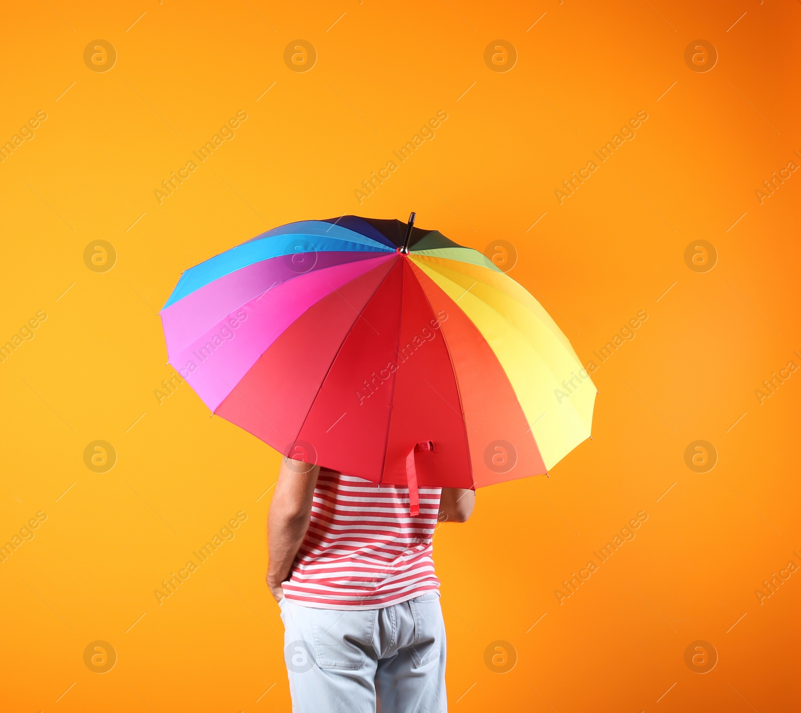 Photo of Man with rainbow umbrella on color background