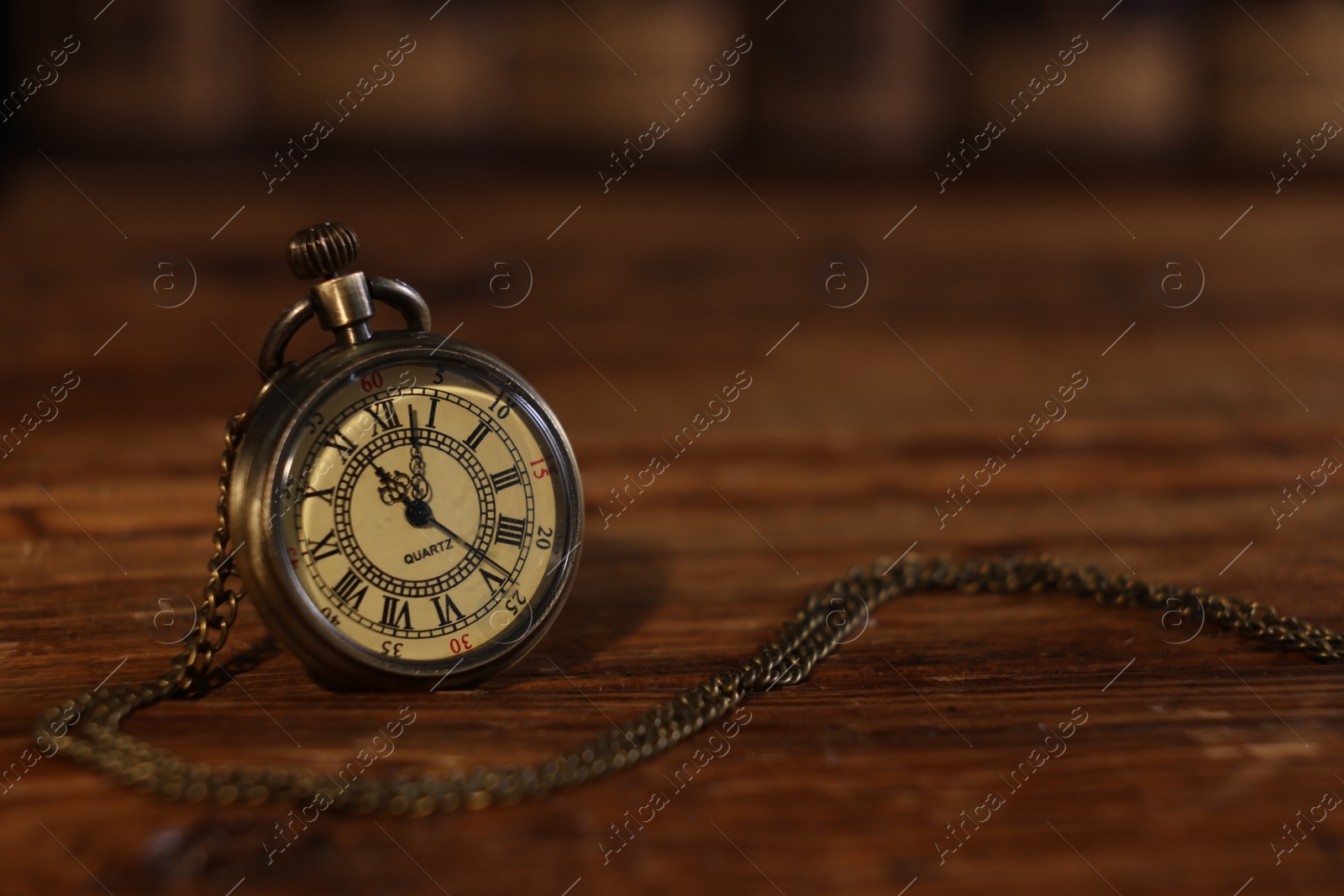 Photo of Pocket clock with chain on wooden table, closeup. Space for text