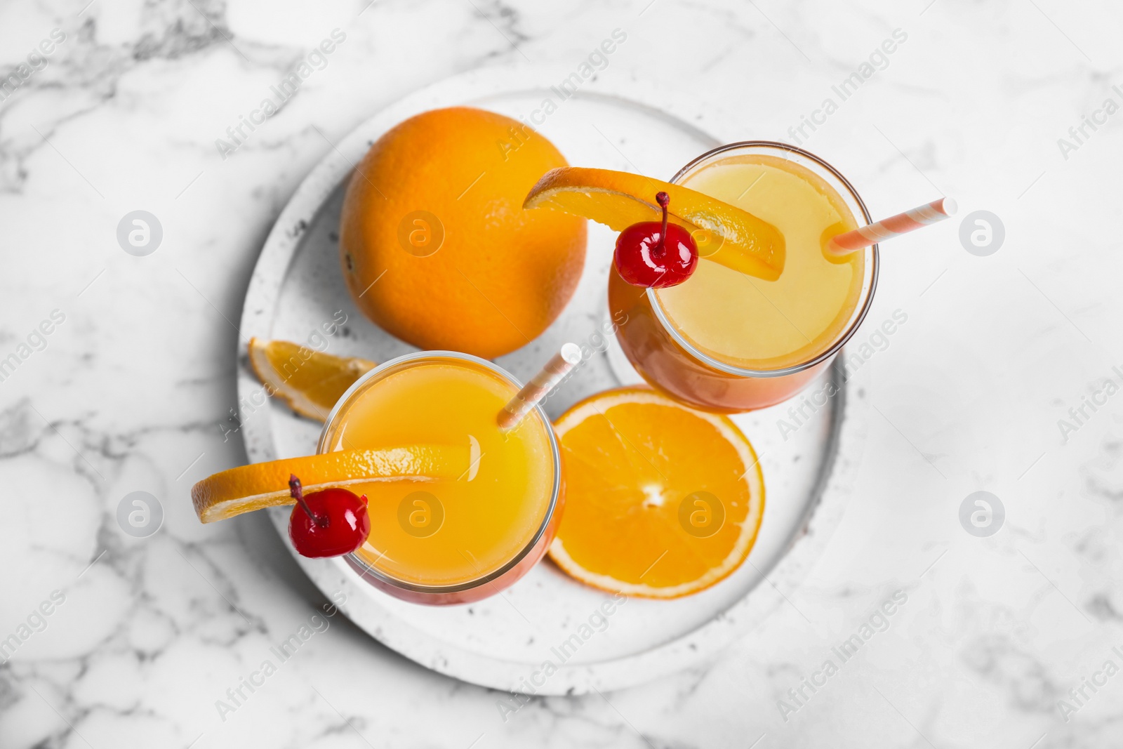 Photo of Fresh alcoholic Tequila Sunrise cocktails on marble table, top view
