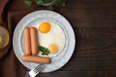 Photo of Delicious boiled sausages and fried eggs served on wooden table, flat lay. Space for text
