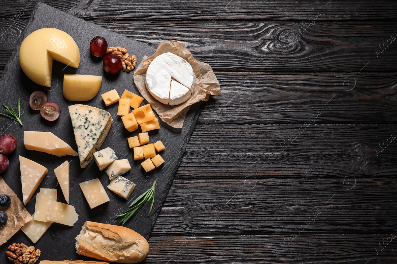 Photo of Different types of delicious cheese served on black wooden table, top view. Space for text