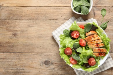 Delicious salad with chicken, cherry tomato and spinach on wooden table, top view. Space for text