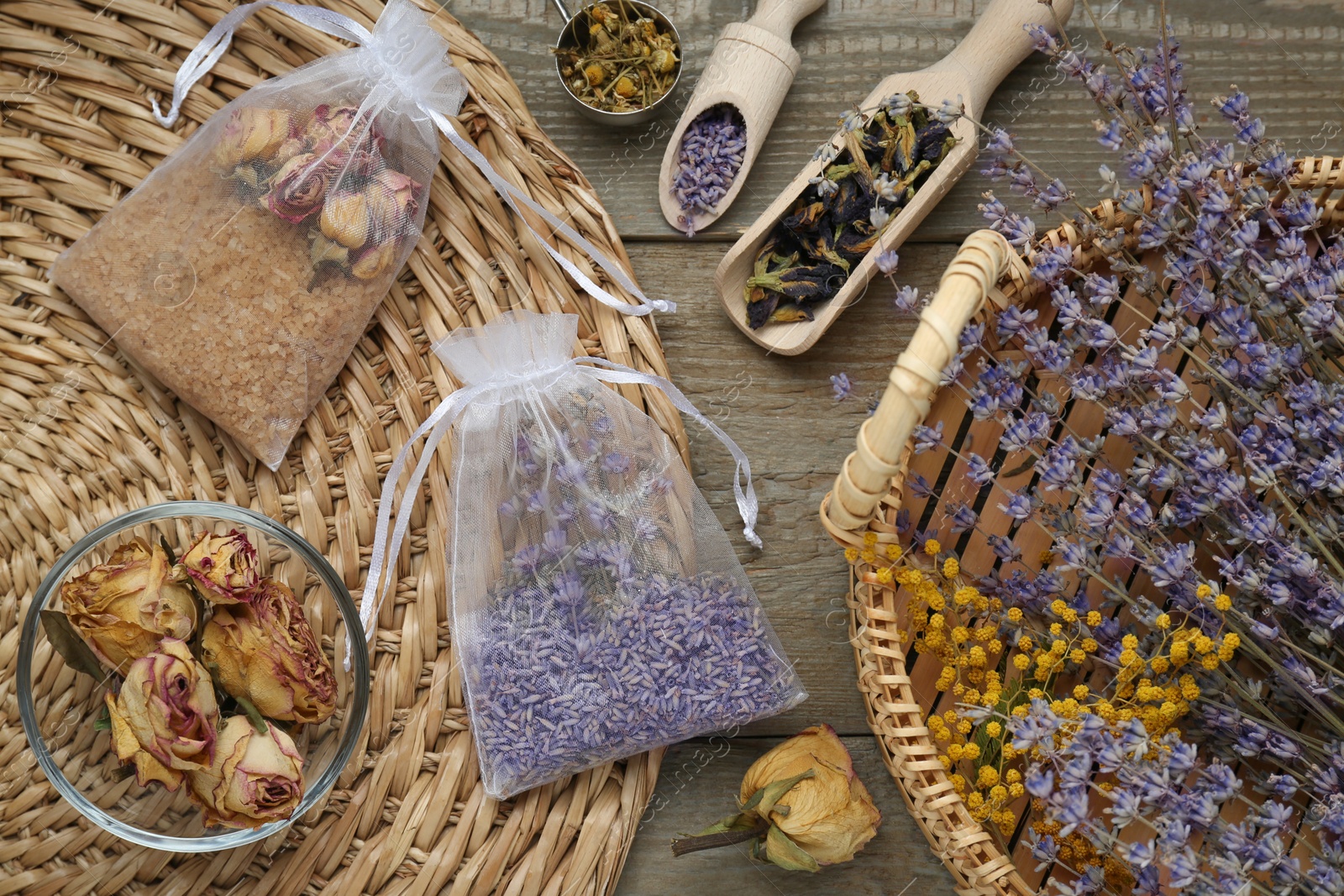 Photo of Scented sachets with dried flowers on wooden table, flat lay