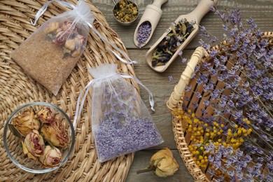 Scented sachets with dried flowers on wooden table, flat lay