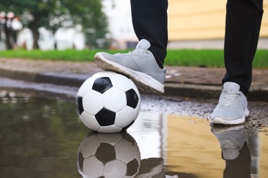 Photo of Man with soccer ball near puddle outdoors, closeup