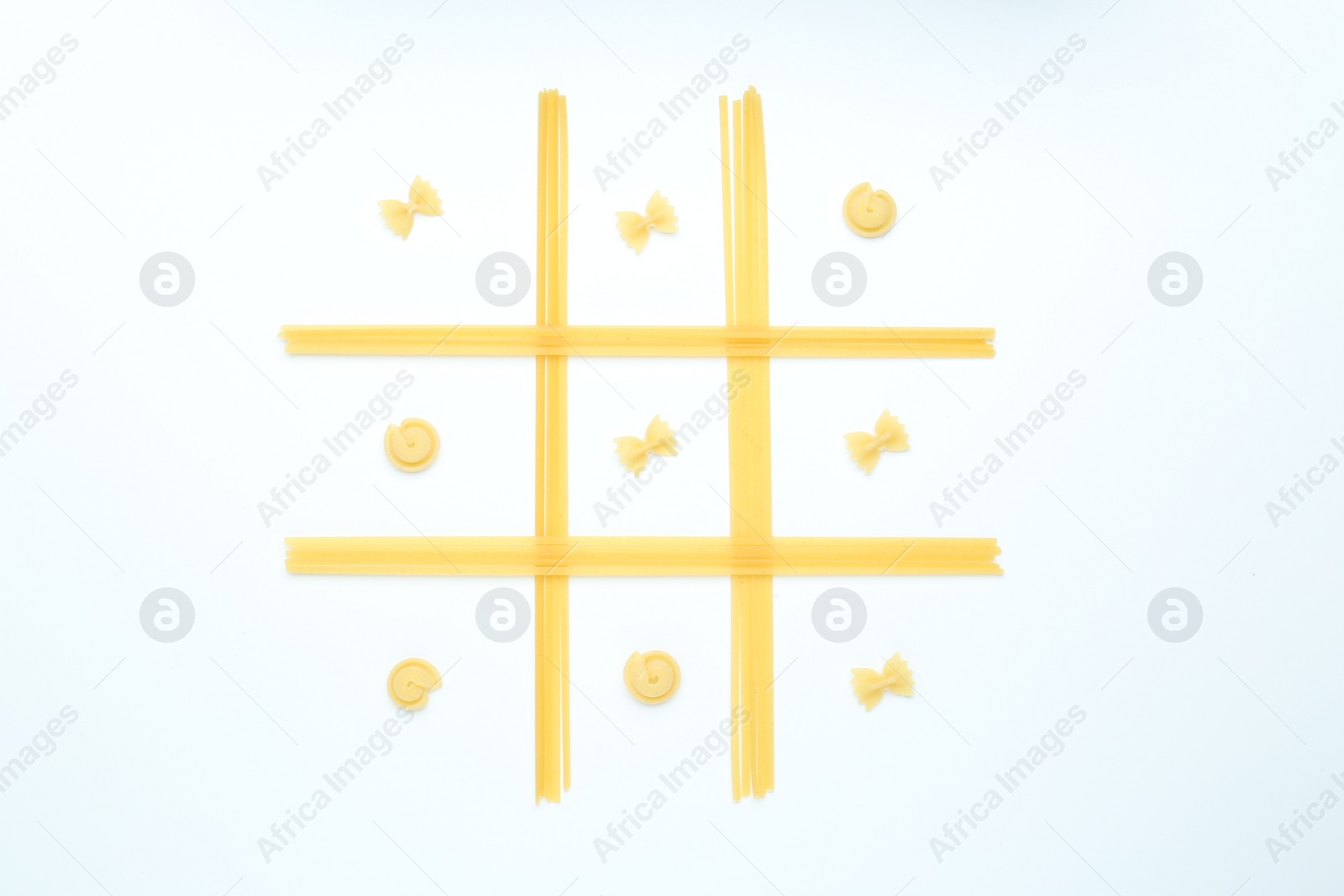 Photo of Tic tac toe game made with different types of pasta isolated on white, top view