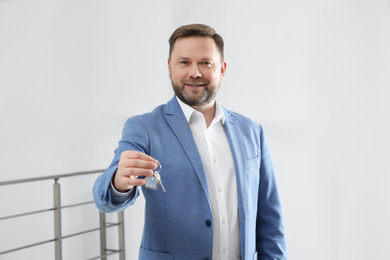 Male real estate agent holding key in new apartment