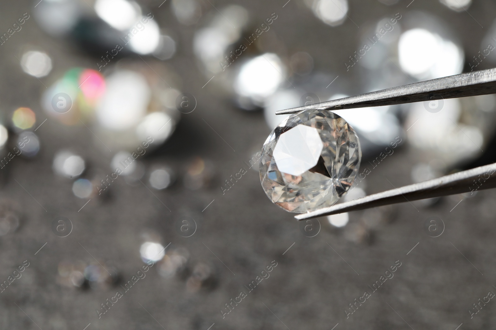 Photo of Tweezers with beautiful gemstone on blurred background, closeup. Space for text
