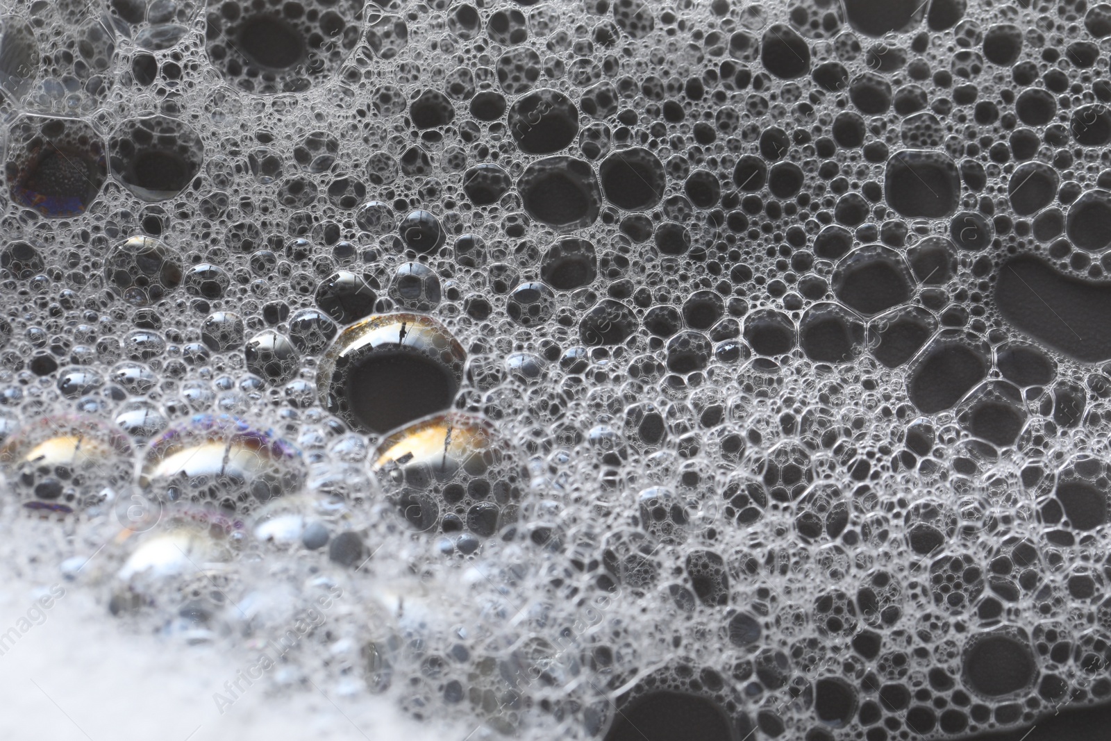 Photo of White washing foam on dark gray background, closeup