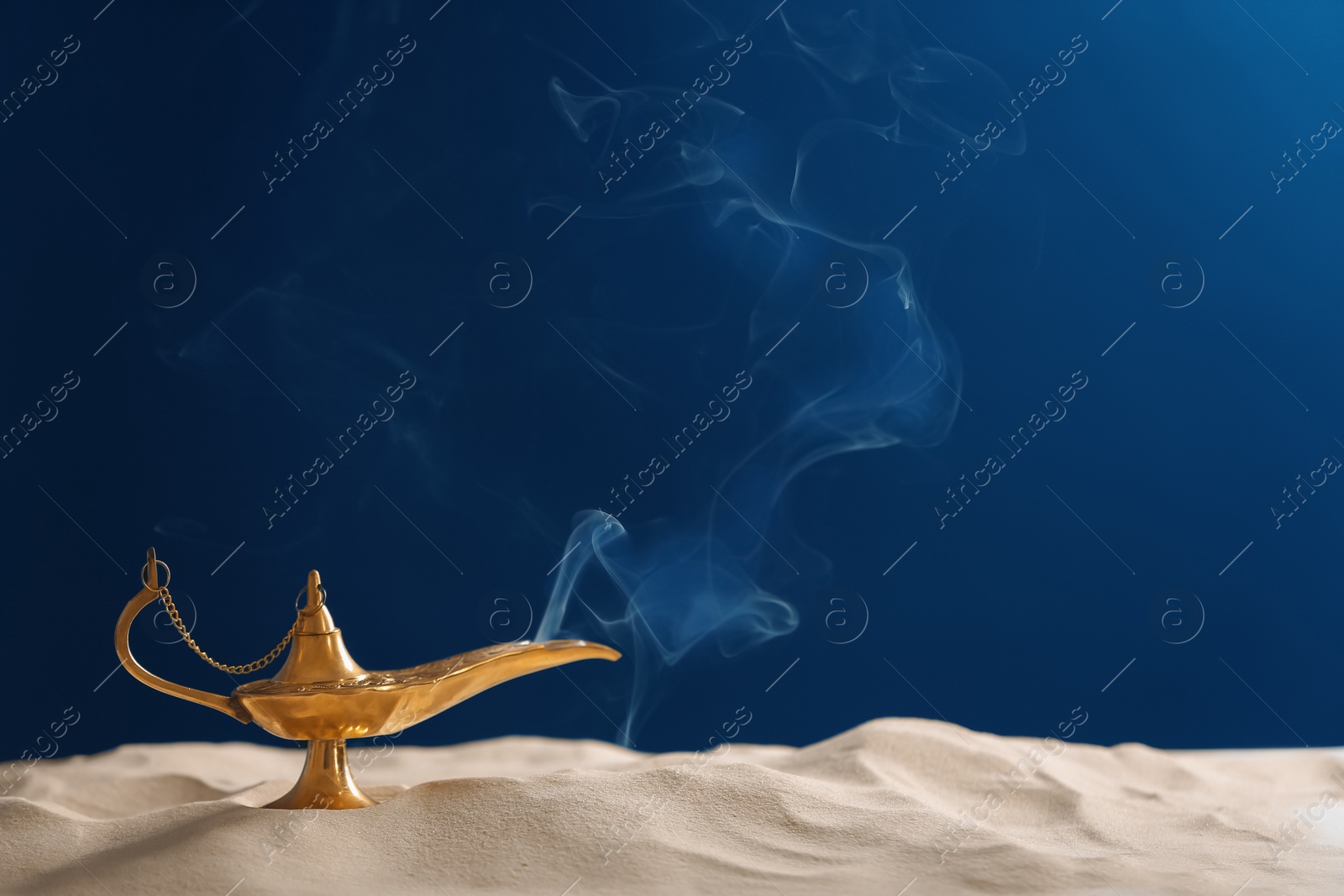 Photo of Aladdin lamp of wishes on sand against dark background