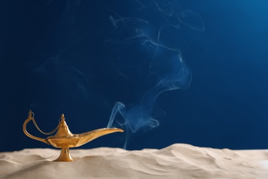 Photo of Aladdin lamp of wishes on sand against dark background