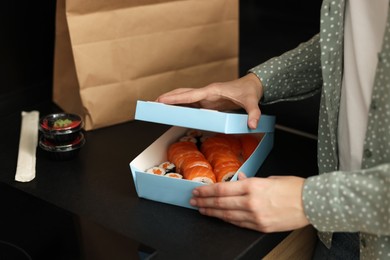 Photo of Woman unpacking her order from sushi restaurant at countertop in kitchen, closeup