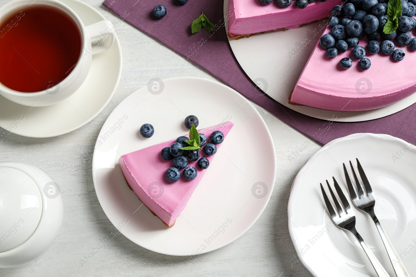 Photo of Flat lay composition of tasty blueberry cake on light table