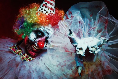 Photo of Terrifying clown on dark background. Halloween party costume