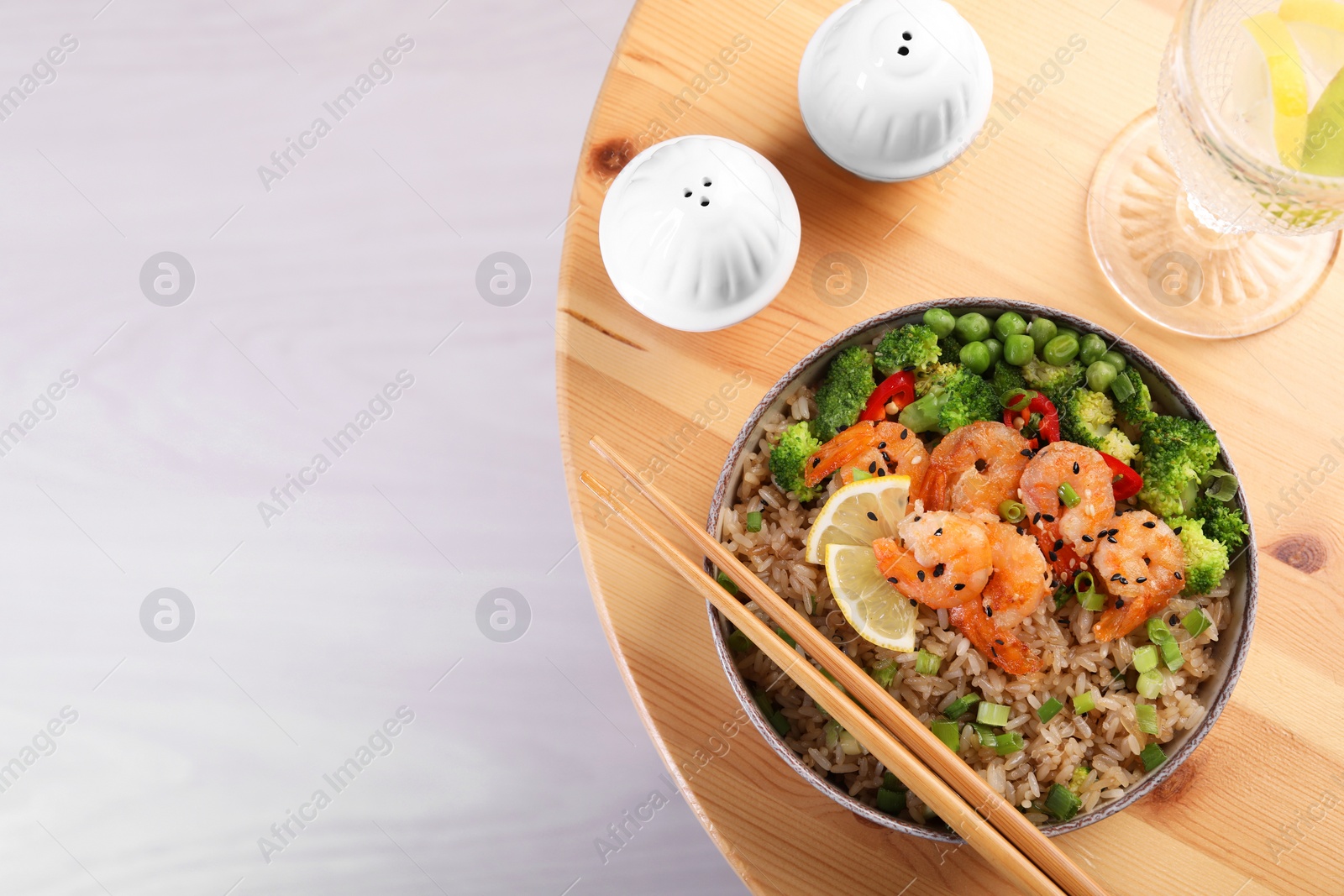 Photo of Tasty rice with shrimps and vegetables served on wooden table, flat lay. Space for text