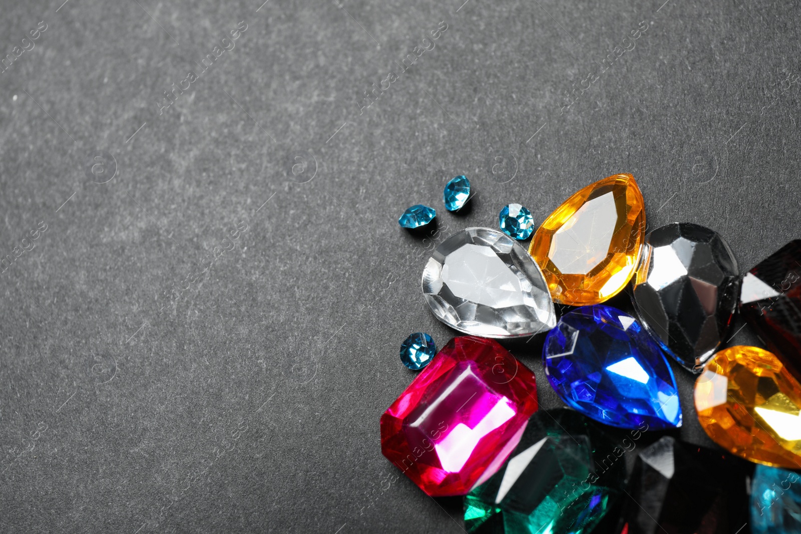 Photo of Pile of different beautiful gemstones on black background. Space for text