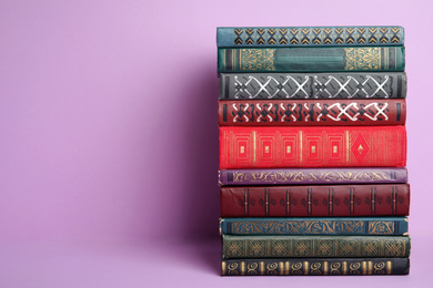 Stack of hardcover books on violet background. Space for text